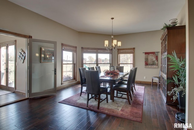 dining space with a wealth of natural light, an inviting chandelier, and dark hardwood / wood-style flooring