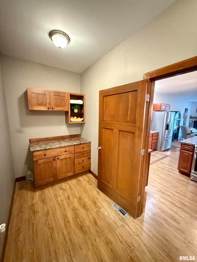 kitchen featuring stainless steel fridge and light hardwood / wood-style floors