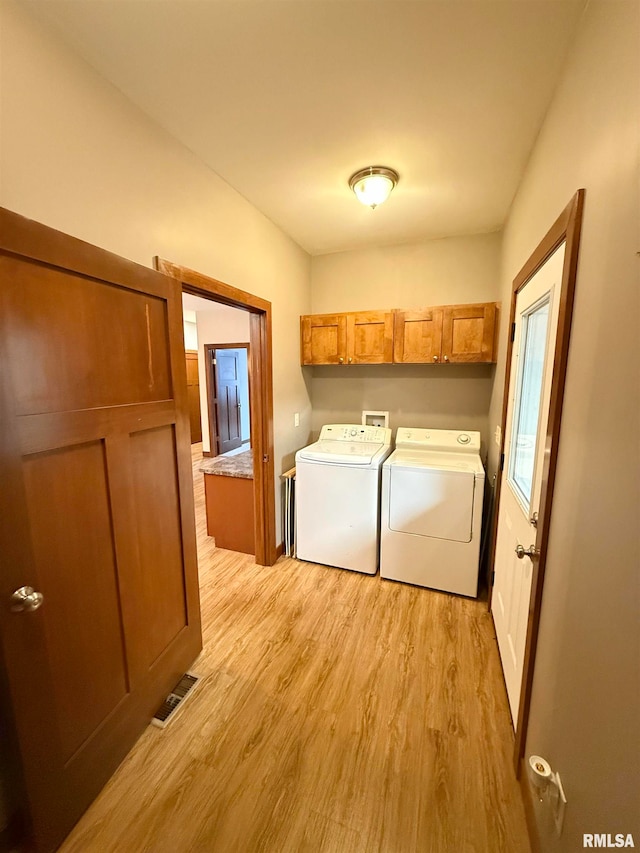 laundry area with washer and dryer, cabinets, and light wood-type flooring