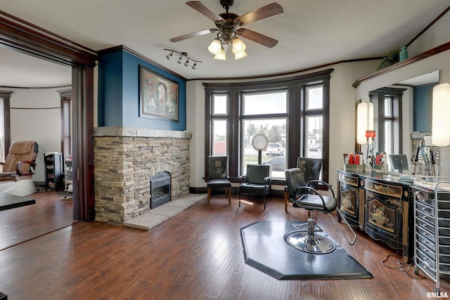 living area with dark wood-type flooring, ornamental molding, and a textured ceiling