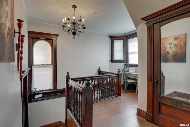 hall with an inviting chandelier, ornamental molding, and wood-type flooring