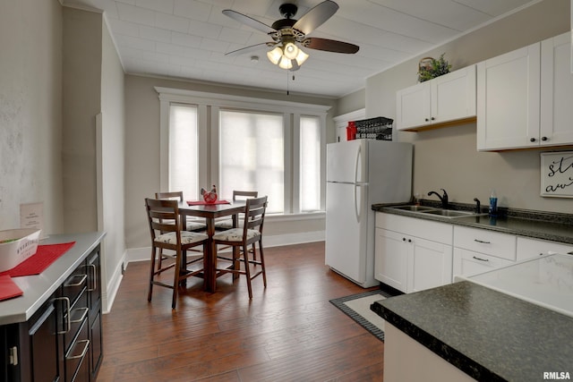 kitchen with white refrigerator, dark wood-type flooring, sink, and white cabinets