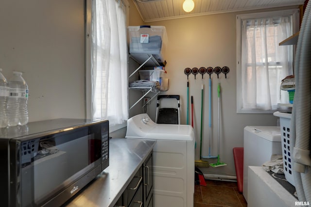 laundry room with independent washer and dryer, a healthy amount of sunlight, and dark tile patterned floors