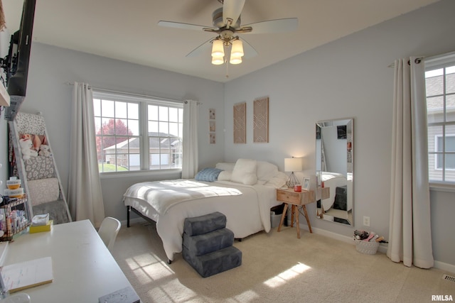 carpeted bedroom featuring multiple windows and ceiling fan