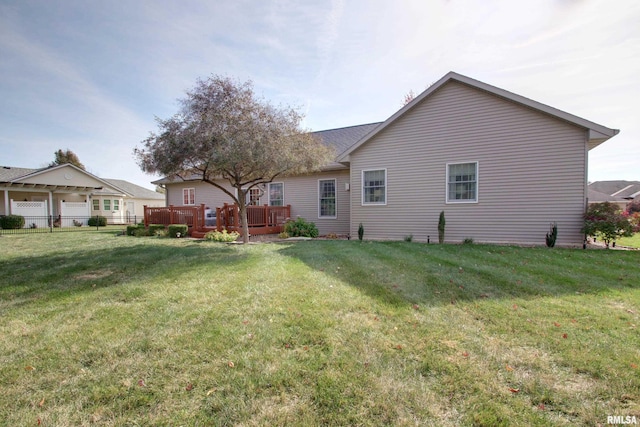 rear view of property with a yard, a wooden deck, and a garage