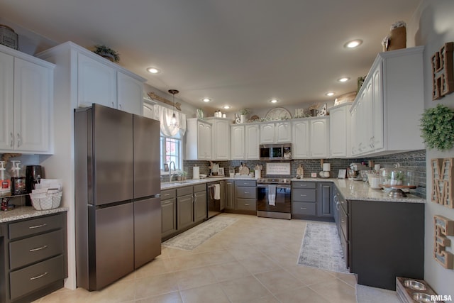 kitchen featuring decorative backsplash, appliances with stainless steel finishes, white cabinetry, light tile patterned flooring, and decorative light fixtures