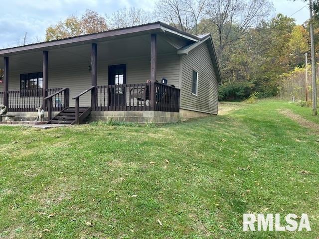 rear view of property featuring a yard and covered porch