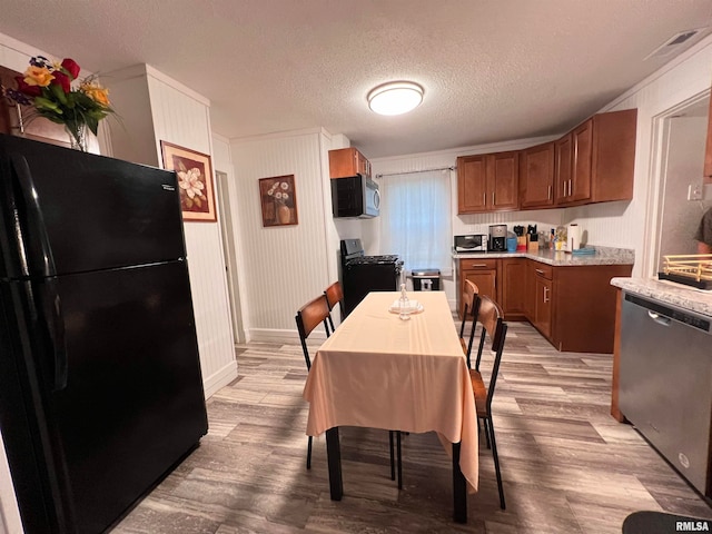 kitchen with light wood-type flooring, a textured ceiling, and appliances with stainless steel finishes