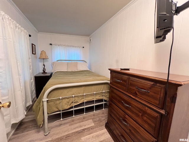 bedroom with ornamental molding and light hardwood / wood-style floors