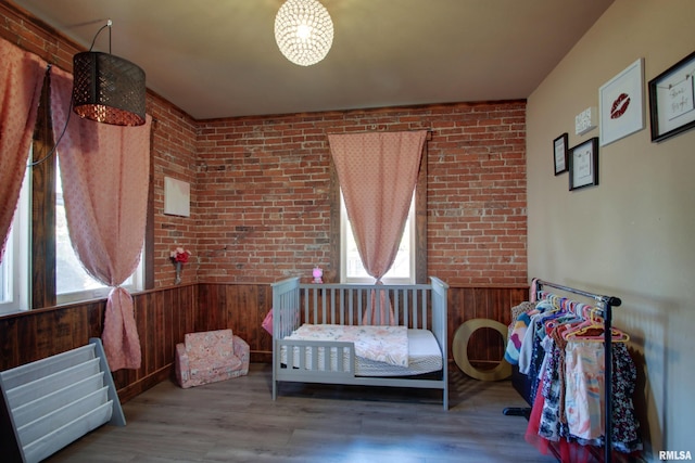 bedroom with brick wall, wood walls, and wood-type flooring