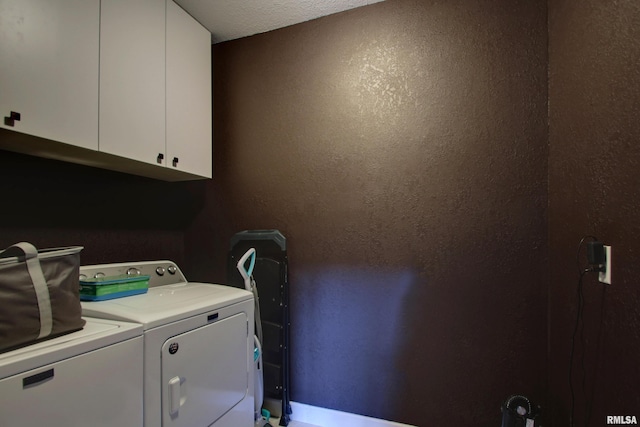 clothes washing area with washer and clothes dryer, a textured ceiling, and cabinets