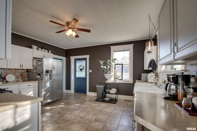 kitchen featuring stainless steel fridge with ice dispenser, backsplash, white cabinetry, pendant lighting, and sink