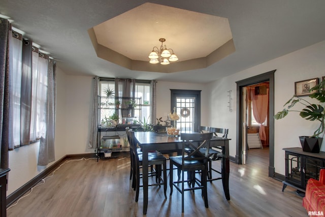 dining room featuring a notable chandelier, a raised ceiling, and hardwood / wood-style floors