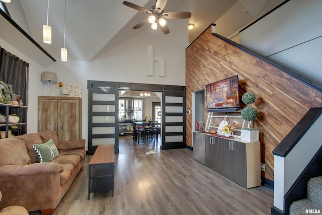 living room featuring a barn door, hardwood / wood-style flooring, high vaulted ceiling, and ceiling fan