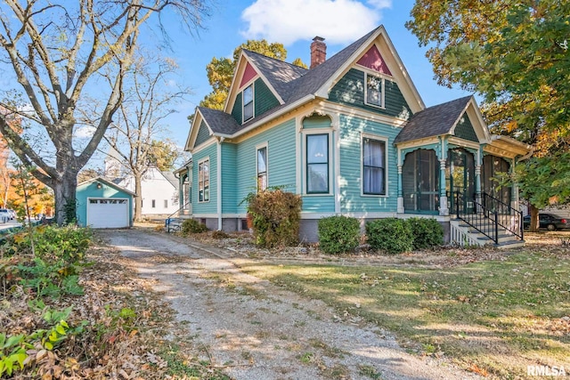 victorian-style house featuring a front yard, an outdoor structure, and a garage