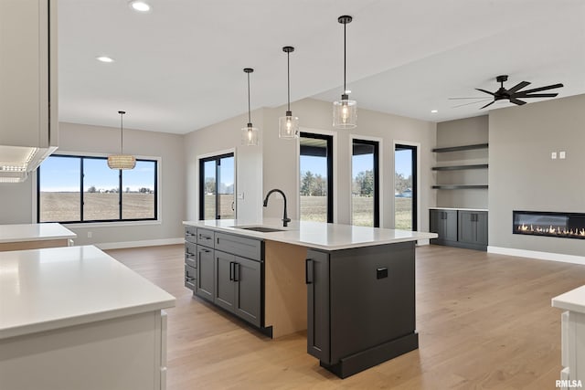 kitchen with gray cabinetry, sink, an island with sink, and a wealth of natural light