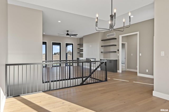 interior space featuring hardwood / wood-style flooring and ceiling fan with notable chandelier