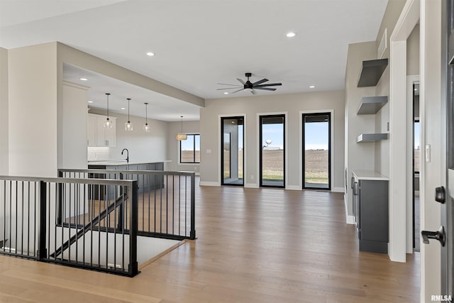 kitchen with ceiling fan, sink, backsplash, light hardwood / wood-style floors, and white cabinets