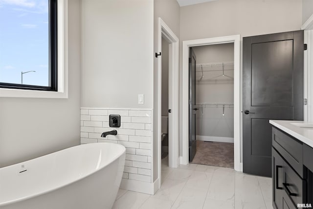 bathroom with vanity, a tub to relax in, and tile walls