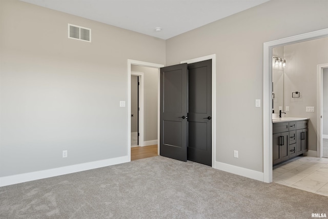 unfurnished bedroom with ensuite bath and light carpet