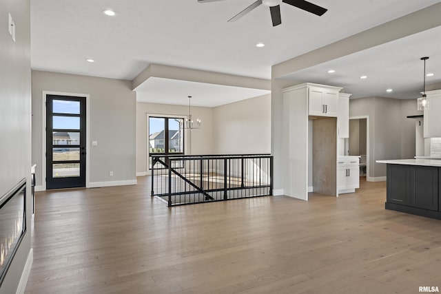 unfurnished living room with hardwood / wood-style floors and ceiling fan with notable chandelier