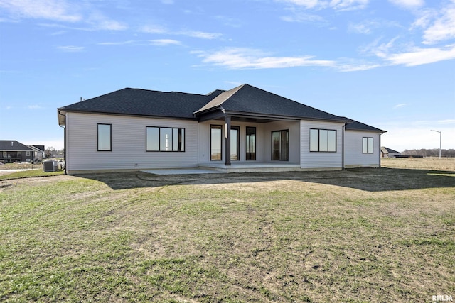 rear view of property with a lawn, a patio area, and central air condition unit