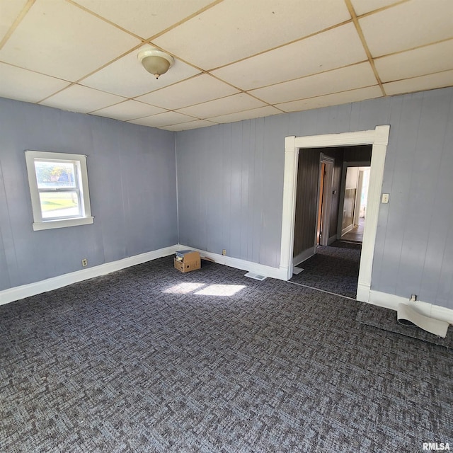 unfurnished room with dark colored carpet and a paneled ceiling