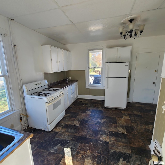 kitchen featuring a drop ceiling, white cabinets, sink, and white appliances