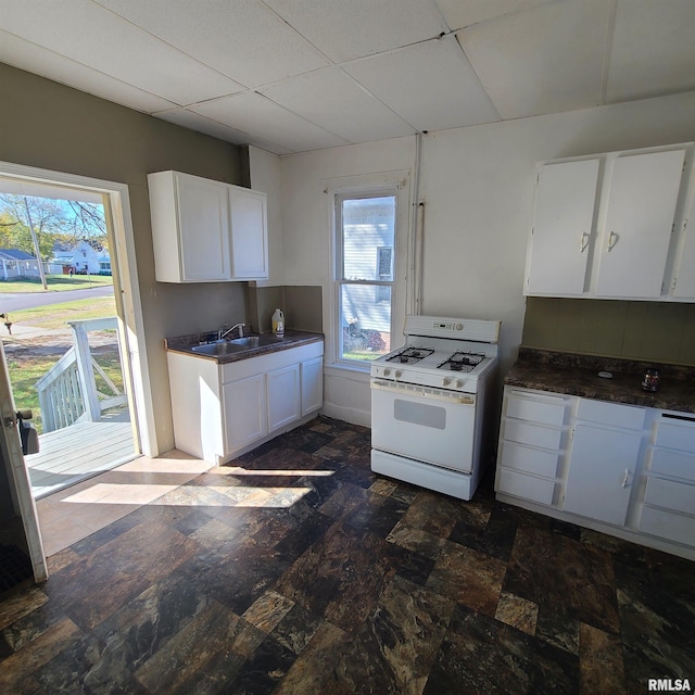 kitchen with a paneled ceiling, white gas range oven, sink, and white cabinets