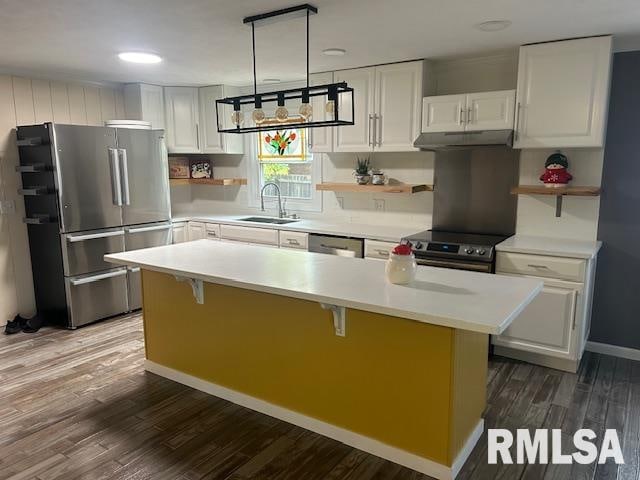 kitchen with white cabinetry, appliances with stainless steel finishes, hardwood / wood-style flooring, and a center island