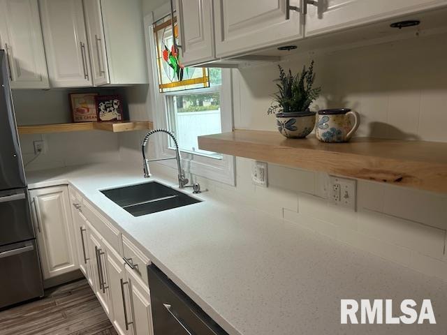 kitchen with dark hardwood / wood-style flooring, appliances with stainless steel finishes, sink, and white cabinets