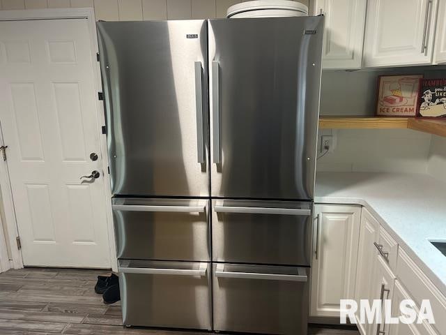 kitchen with white cabinetry, hardwood / wood-style flooring, and stainless steel refrigerator