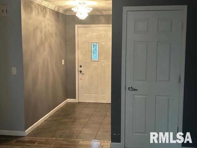 foyer entrance featuring wood-type flooring, crown molding, and a notable chandelier