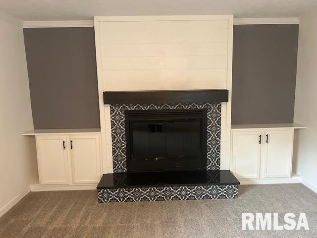 details with a tiled fireplace, crown molding, and carpet floors