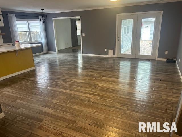 unfurnished living room with dark hardwood / wood-style flooring, a chandelier, and crown molding