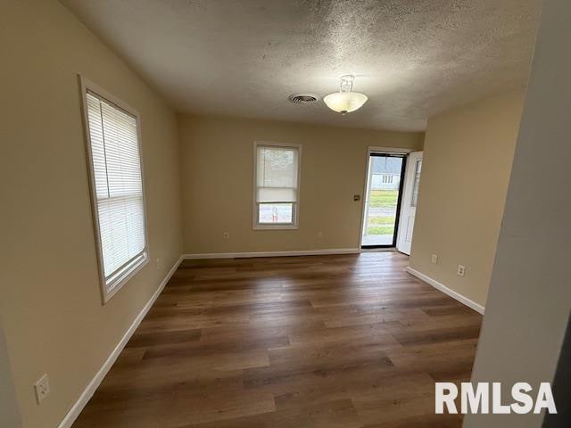 unfurnished room with a textured ceiling and dark hardwood / wood-style floors