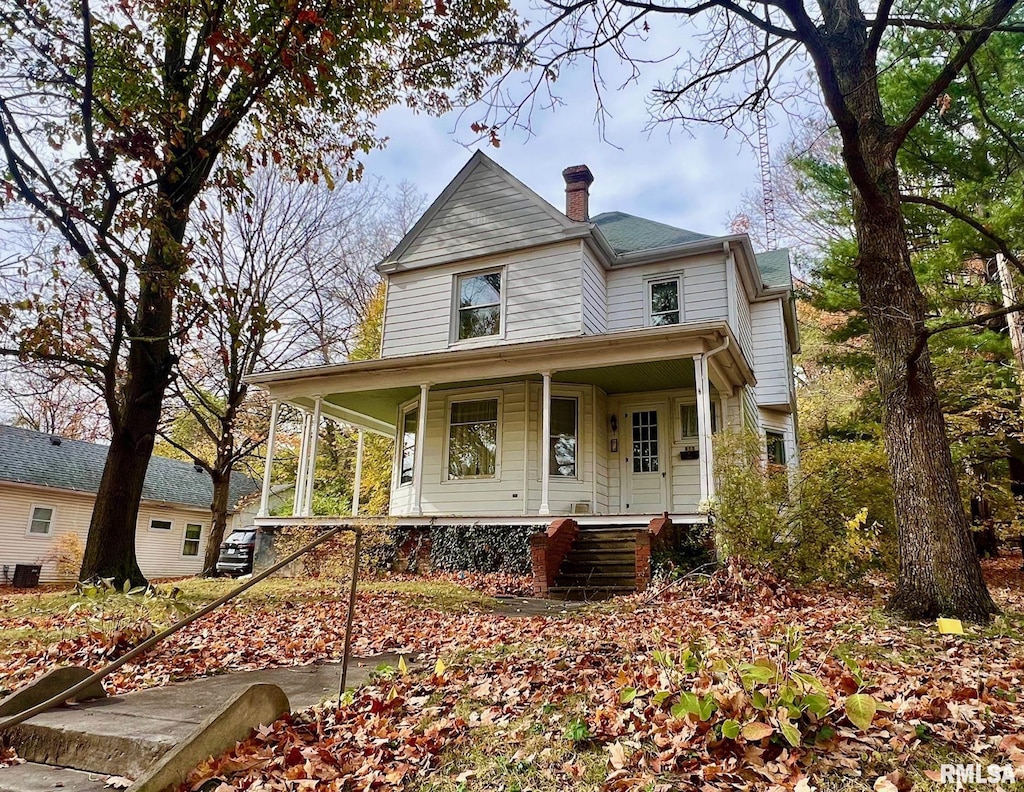 victorian home with covered porch and a chimney