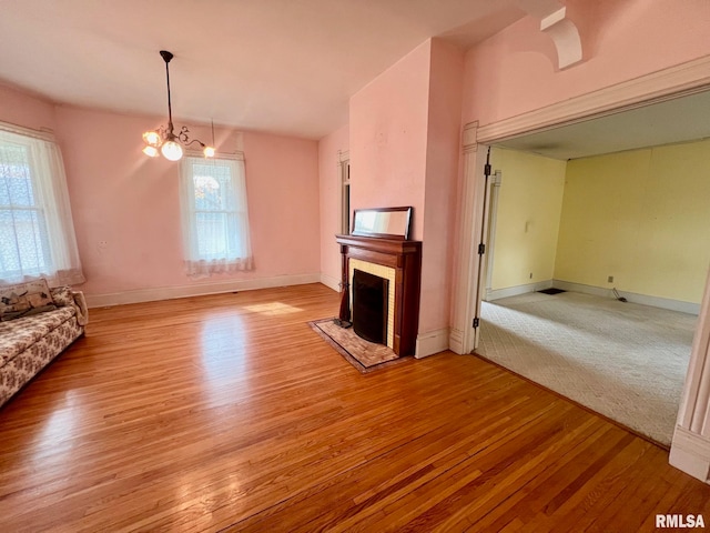 unfurnished living room featuring a chandelier, a healthy amount of sunlight, and light hardwood / wood-style flooring