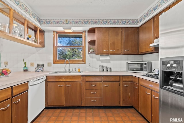 kitchen featuring a sink, open shelves, stainless steel appliances, light countertops, and tasteful backsplash