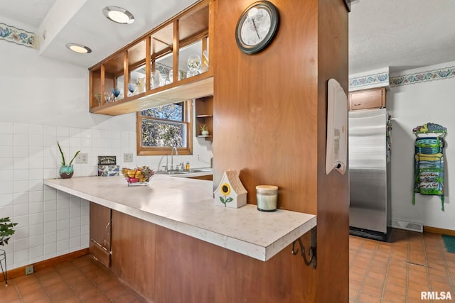 kitchen featuring stainless steel refrigerator, dark tile patterned flooring, and brown cabinets