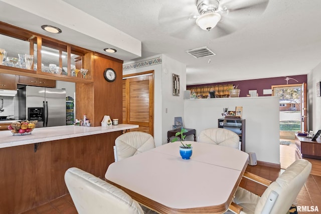 tiled dining space with ceiling fan and a textured ceiling