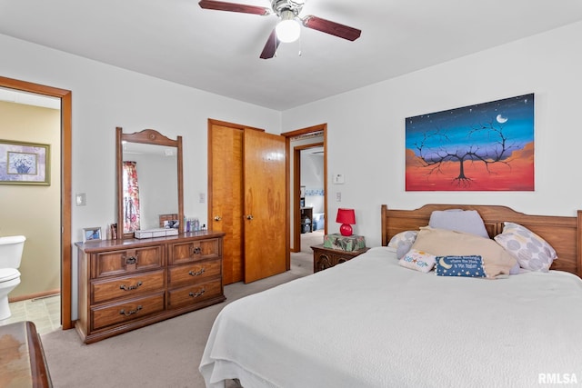 bedroom with a closet, light colored carpet, ceiling fan, and ensuite bathroom