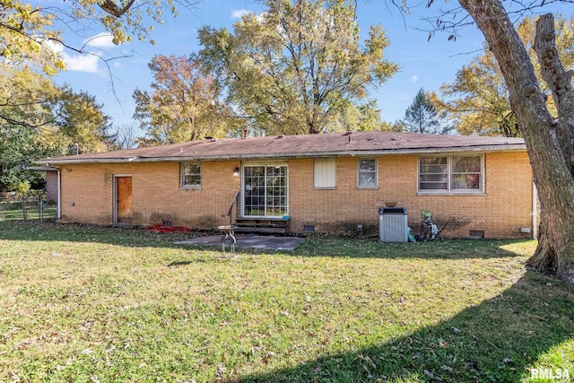 rear view of house featuring a patio area, crawl space, brick siding, and a lawn