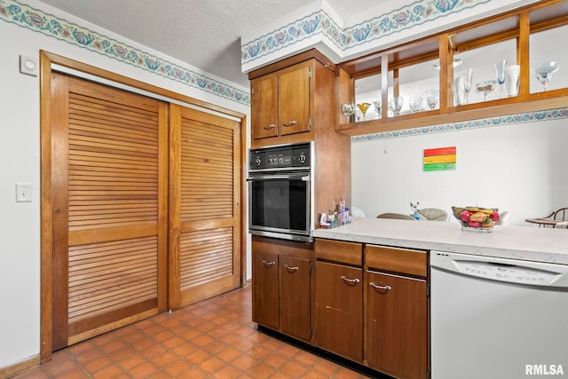 kitchen featuring black oven, brown cabinets, a textured ceiling, dishwasher, and light countertops