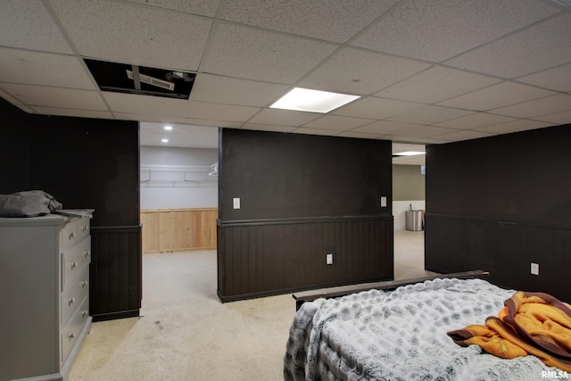 carpeted bedroom with wood walls, a closet, a walk in closet, and a drop ceiling