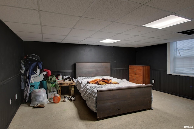 carpeted bedroom featuring a paneled ceiling and wooden walls