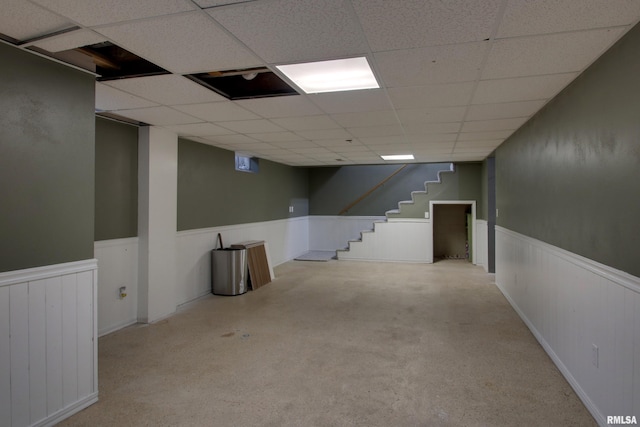 basement with a paneled ceiling and light carpet