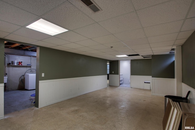 basement with a drop ceiling and washer / clothes dryer