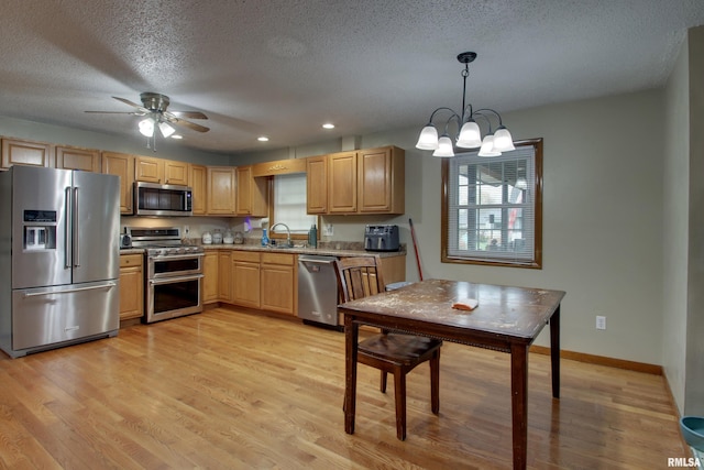 kitchen featuring stainless steel appliances, a textured ceiling, hanging light fixtures, light hardwood / wood-style floors, and ceiling fan with notable chandelier