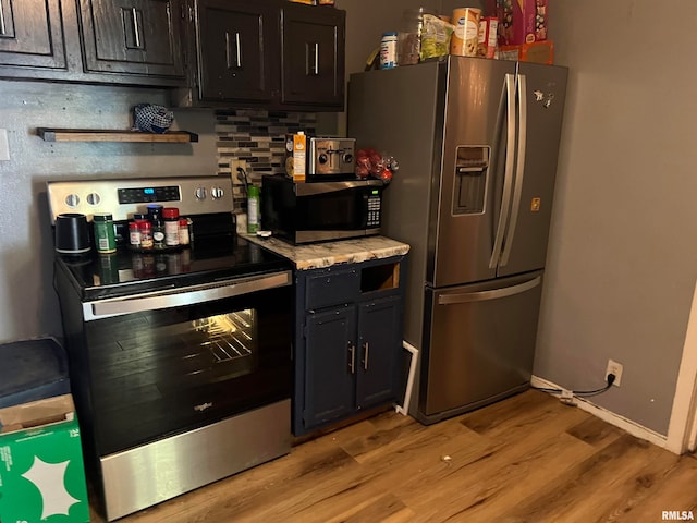 kitchen with light wood-type flooring, appliances with stainless steel finishes, and tasteful backsplash